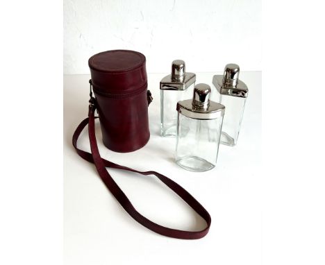 A leather cased triple flask set for sporting or field use - the three nested, flush-fitting glass and plated metal flasks in