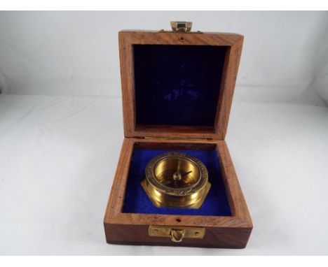 A brass compass contained in a wooden box