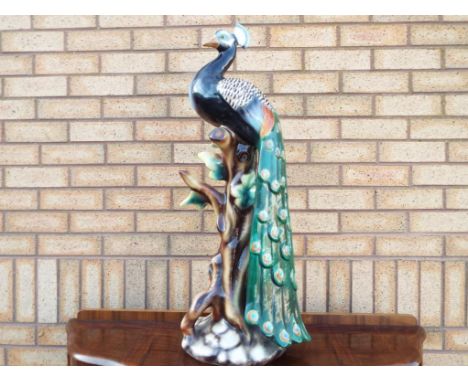 A large Italian ceramic model depicting a perching peacock, approximately 81 cm (h) in very good condition