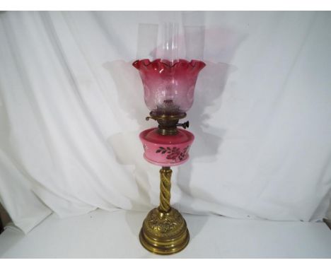 A vintage duplex oil lamp with brushed body, hand painted opaque pink front glass with floral and foliate decoration and cran