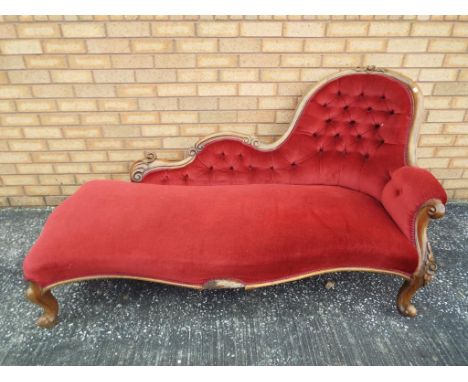 A Victorian oak framed spoon back chaise longue with upholstered finish with button back detailing 88 cm x 165 cm x 90 cm. Es