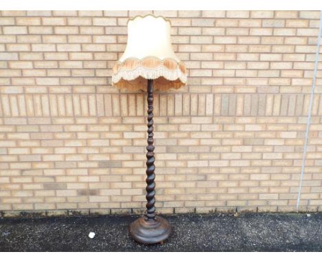 A good quality solid oak standard lamp with barley twist support and large cream and gold coloured shade, height without shad