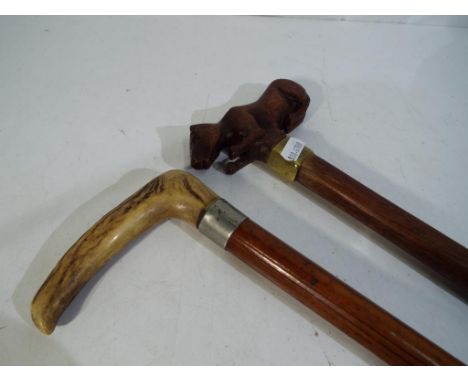 A walking stick with the handle in the form of a dog and a further bone handled walking stick. Estimate £30 - £50