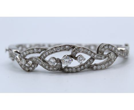 A diamond set hinged bangle in white precious metal. Set with 73 vari sized round brilliant cut diamonds to an estimated tota