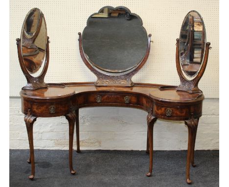 An Edwardian figured walnut veneer dressing table of concave form with fixed central and rotating side mirrors, raised on sle