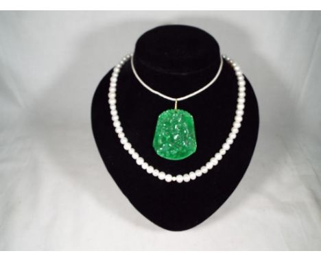 An Apple jade Chinese carved pendant with a pearl necklace, 49.5 cm (necklace) Jade 5.3cm x 4.5cm x 0.5cm. Estimate £40 - £60
