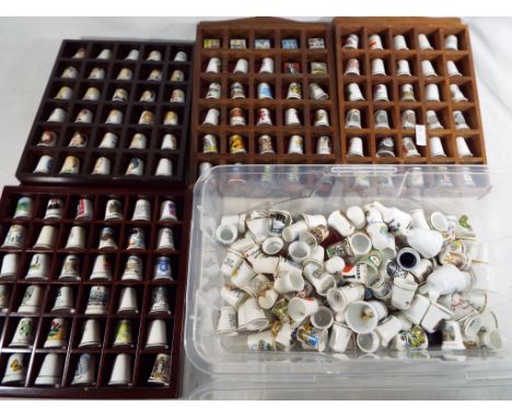 A collection in excess of 200 ceramic thimbles, and four wall mounted wooden display cabinets