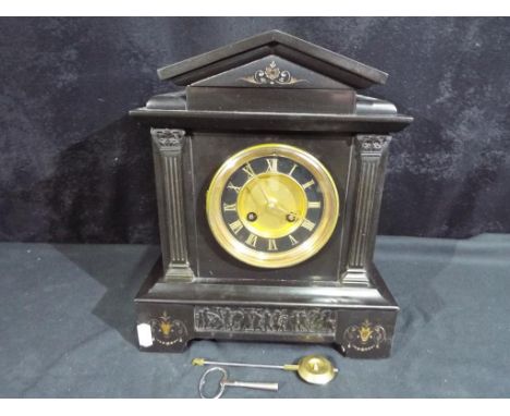 A French black marble mantel clock of architectural form flanked by square, reeded columns, Corinthian capitals, incised, gil