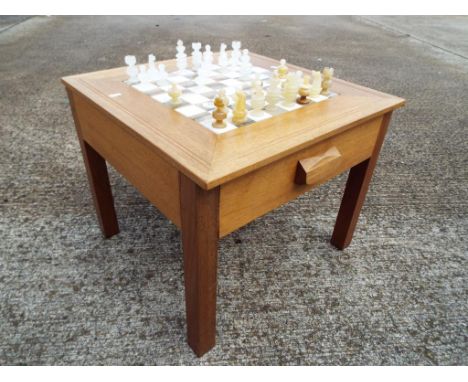 A light wood table with twin drawers, the table inset with marble chess board, and full set of onyx chess pieces, 47 cm x 57 