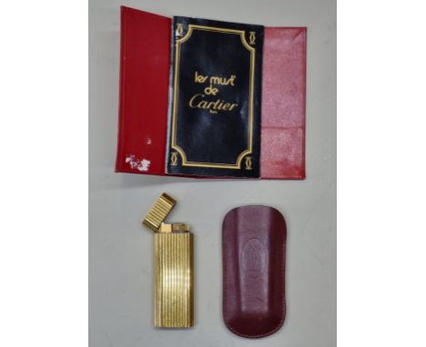 A vintage Cartier gilt lighter, No.44921D, with leather sleeve and booklet. 