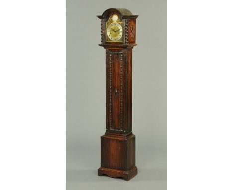 An oak three-train grandmother clock, with silvered brass dial, applied mouldings to the case and raised on bracket feet.  He