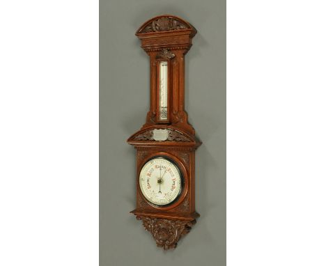 A large late Victorian aneroid barometer, with mercury thermometer, in foliate and scroll carved oak case.  Height 101 cm (se