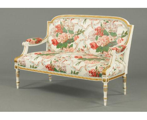 A late 19th century parlour settee, white and gilt painted and with foliate patterned material.