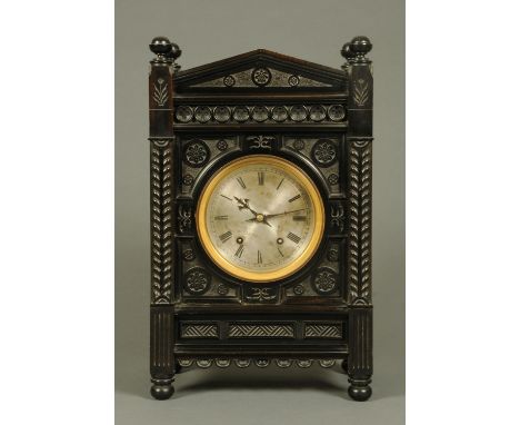 An Arts & Crafts ebonised bracket clock, with triangular pediment and carved case, with circular silvered brass dial, Roman n