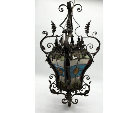 A turn of the century wrought iron lamp with stained glass panels. One panel is loose but present. 