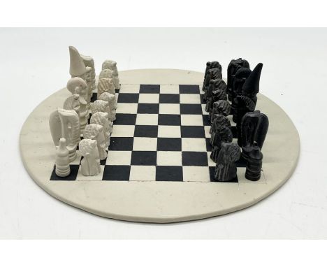 A hand carved small soapstone chess set on matching board - two pieces A/F