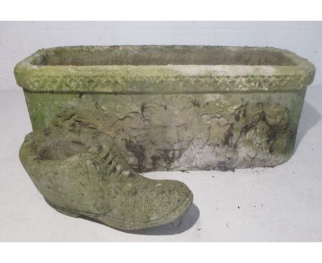 A reconstituted stone garden trough with a lion's head decoration to side along with a stone boot.