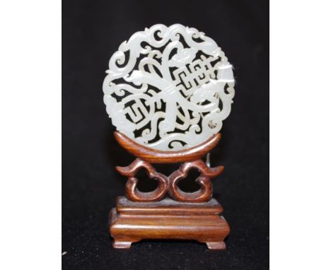 Chinese carved Jade disc on a timber stand 9.5cm high approx.