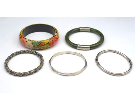 A group of five bangles includes two sterling silver pieces and a "spinach jade" piece