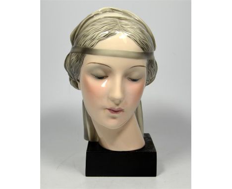 A Goldscheider pottery bust of a lady with a head band, wearing a grey shawl, on a square ebonised base. Height 20cm.