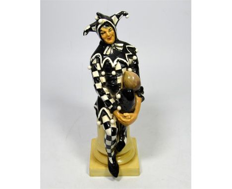 A Royal Doulton figure of a Jester HN45, wearing a black and white chequered cloak, circa 1920. Height 24.5cm.