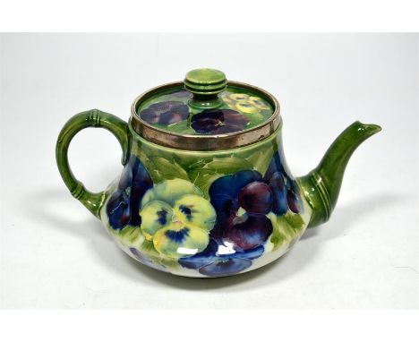 A William Moorcroft for James Macintyre 'Pansy' teapot with silver rim decorated on a white background, circa 1905. Signed Wi