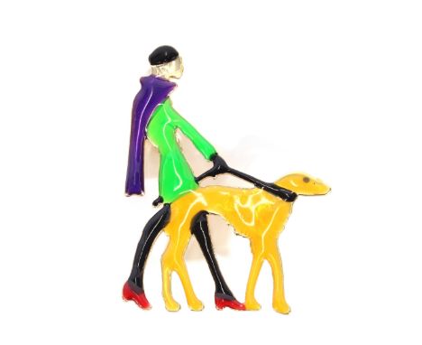An Art Deco design yellow metal and enamel decorated brooch, depicting a lady walking a dog