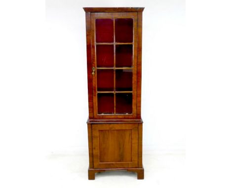 A 19th century walnut veneered narrow bookcase, single glazed door with eight panes, brass drop handle, enclosing three adjus