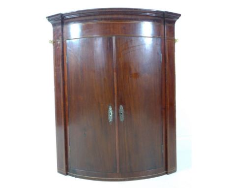 An early Victorian bowfront mahogany and line inlaid corner cupboard, twin doors enclosing three fixed shelves, interior pain