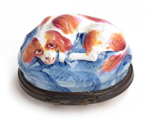 A Bilston enamel oval bonbonnière c.1770, modelled as a red and white spaniel seated on a blue cushion, the metal-mounted and