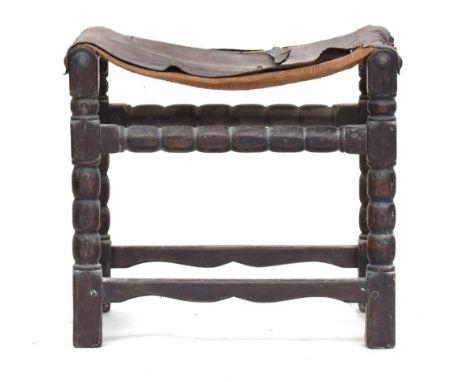 A 17th century style oak stool with leather saddle seatProvenance: from the estate of Elizabeth Pepys-Cockerell, whose husban