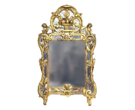 A late 18th century Continental carved giltwood wall mirror, the rectangular central plates surrounded by shaped plates and t