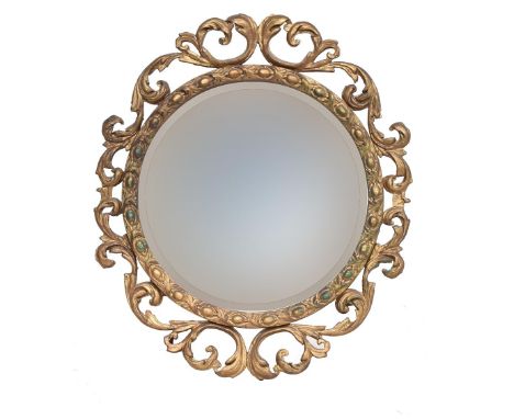 A circular giltwood wall mirror, the bevelled plate surrounded by bead moulding within an openwork scroll border, label to ve