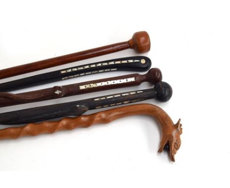 A fruit wood walking cane, a carved dragon mask with bead in mouth above a twisted neck; three other canes with mother of pea
