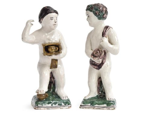 A pair of pottery figures of boys lightly draped in scarves, one holding a rose, the other holding a foot warmer, on square b