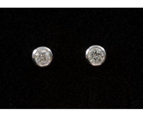 Pair of diamond stud earrings, round brilliant-cut diamonds in a rub-over setting. Total diamond weight approx 0.50 ct