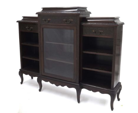 Carved mahogany breakfront bookcase, the caddy tops over frieze drawers above open shelved sections, the central with glazed 