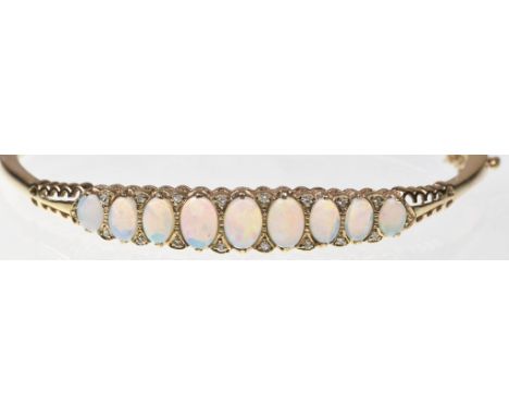 An opal and diamond set bangleThe oval opal cabochons, of graduated from, with single-cut diamond highlights, to pierced scal