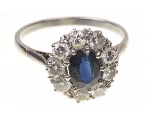 A diamond and sapphire cluster ring   The oval-shaped sapphire, to a round brilliant-cut diamond surround, to an unmarked whi
