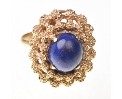 A lapis lazuli cluster ringThe oval lapis lazuli, to a textured double row yellow metal surround, unmarked, ring size P ½ 