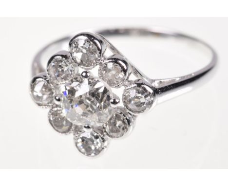 A diamond cluster ringThe central old mine-cut diamond, to a lozenge shaped surround, composed of alternating sized bezel set