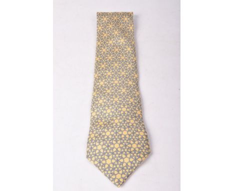 A Hermes silk tieOf typical form with blue and cream printed rope design to a light mustard ground, 145cm long, in original b