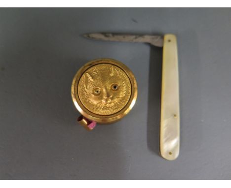 An interesting sewing tape measure in gilt case with cats face - Diameter 2.5 cm - tape end thread bare and a mother of pearl