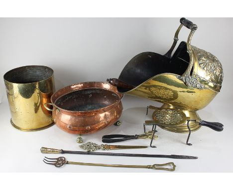 A brass coal bucket with floral design, a large brass shell case, a copper pan on claw and ball feet, a brass trivet and five