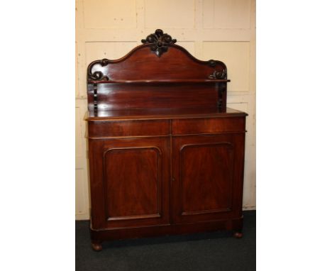 A Victorian mahogany sideboard with raised shelf back and carved scroll surmount, rectangular moulded top, two drawers and cu