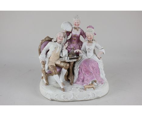A bisque porcelain nodding head figure group of two chess players and a lady with fan in 18th century attire, 24cm high