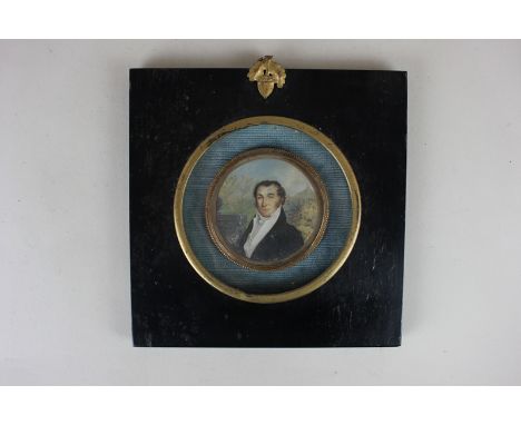 A 19th century circular portrait miniature depicting a gentleman before a garden, in circular gilt metal frame, 6cm diameter