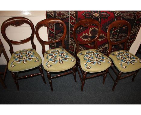 A set of four balloon back dining chairs with floral tapestry seats, on turned legs and stretchers