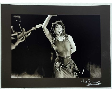 A high-quality print on thick paper stock of an image depicting Kate Bush onstage in 1979. Measures 39.5x30cx. Signed by phot