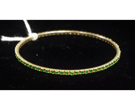 A gold coloured metal and emerald chip bangle, 6.3g